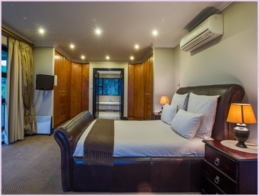 The main bedroom of the Zimbali Holiday Home's Acaciawood villa, showing it's HD TV and en-suite bathroom